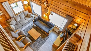 A cozy cabin interior with a sofa, chairs, a coffee table, and a fireplace.