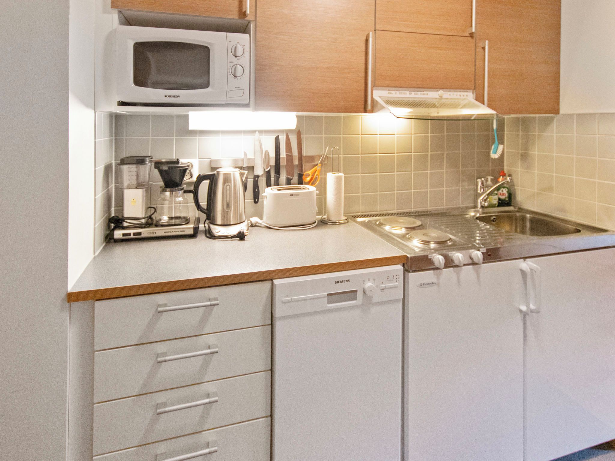 A kitchen with a microwave, coffee maker, toaster, and dishwasher.