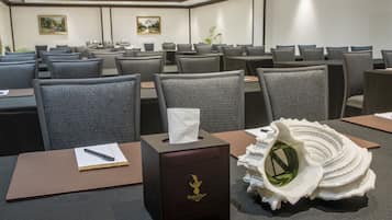 A hotel conference room with rows of gray chairs, a tissue box, and a decorative shell on the table.