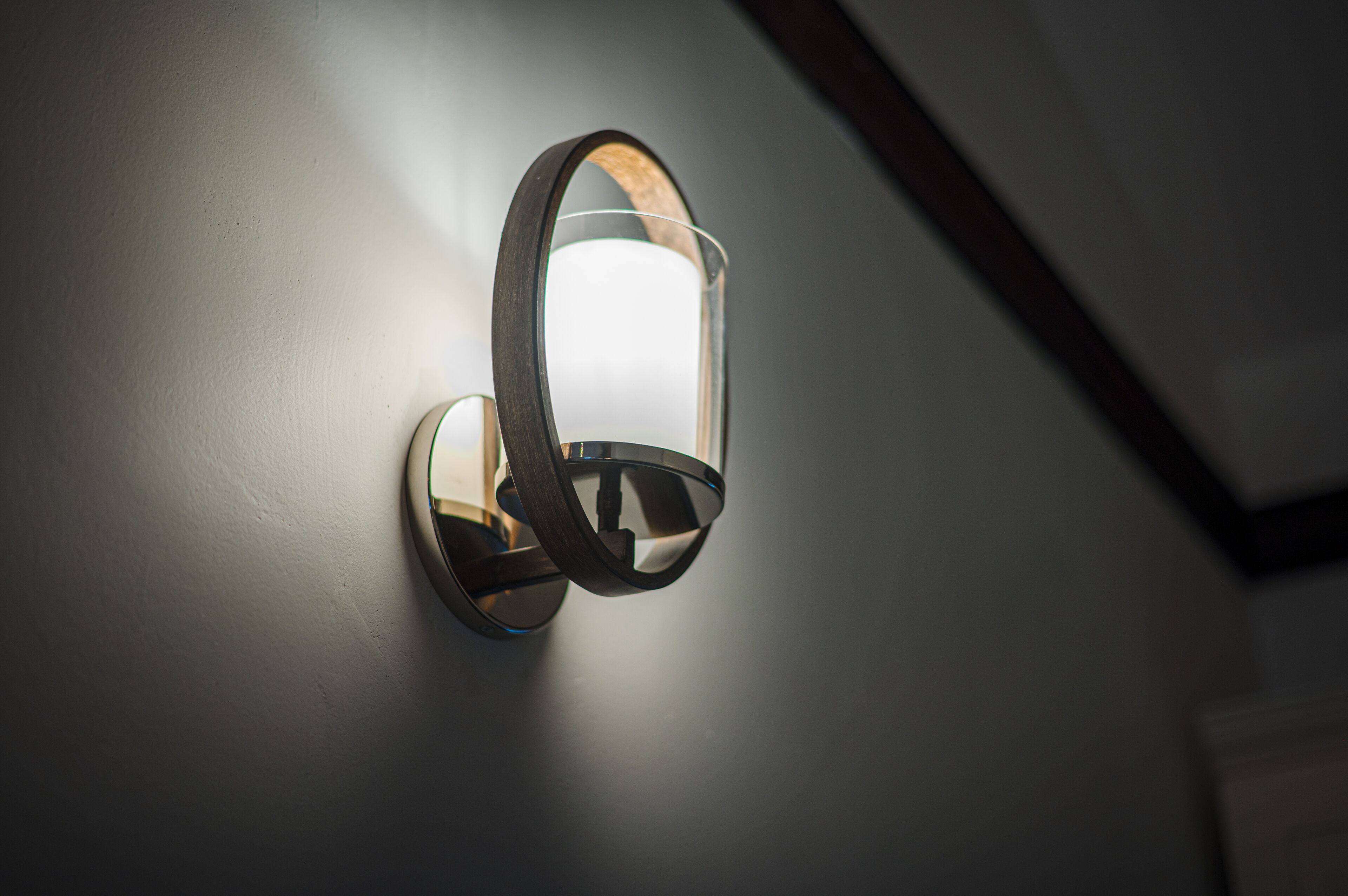 A wall-mounted light fixture with a rectangular glass enclosure and a wooden frame.