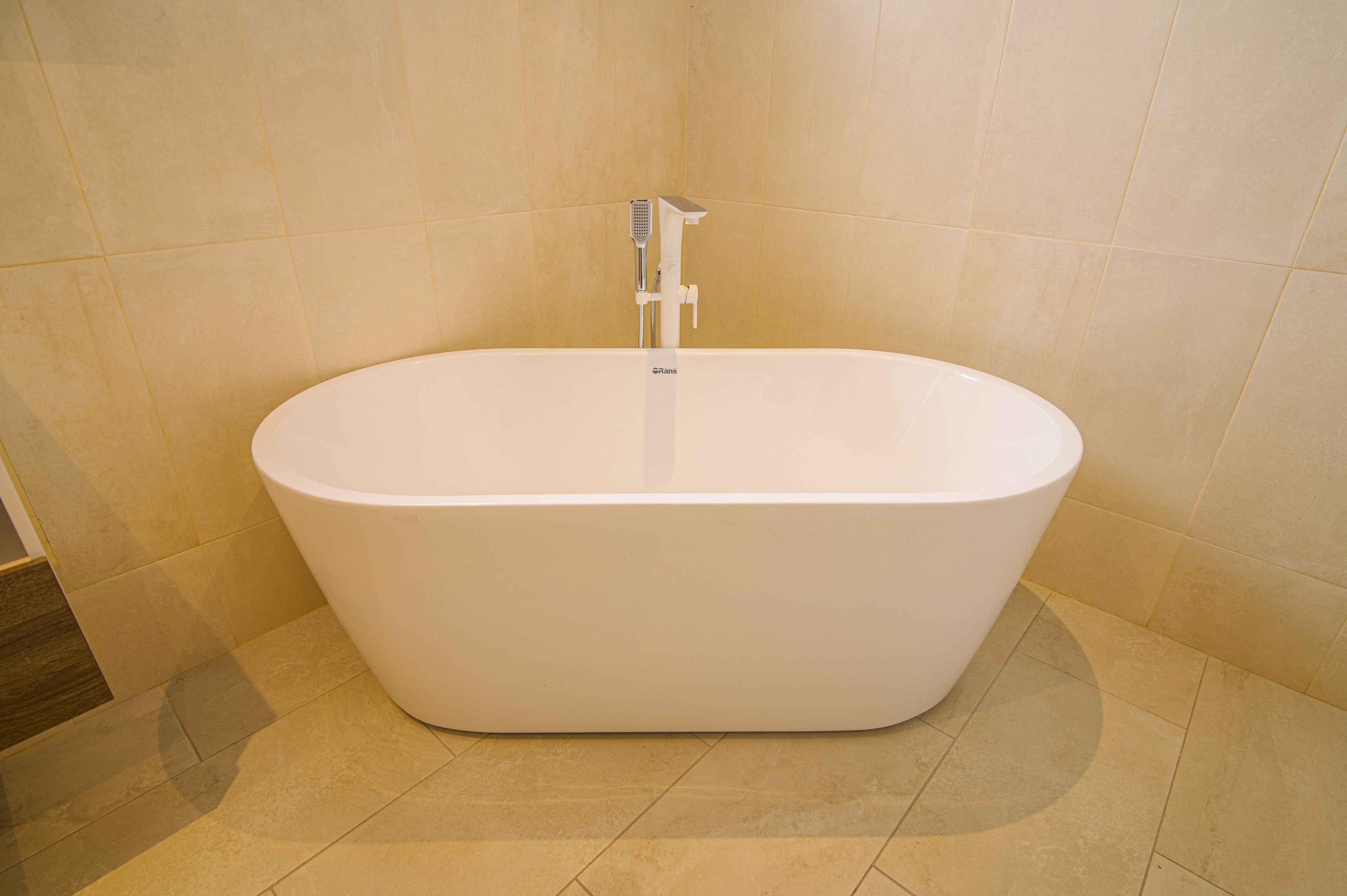 A modern bathroom with a freestanding bathtub, a handheld showerhead, and a wall-mounted faucet.