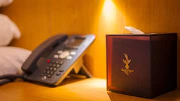 A hotel room with a telephone and a tissue box on a wooden surface.