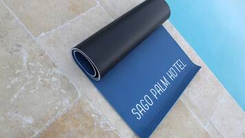 Een blauwe mat met de tekst 'SAGO PALM HOTEL' op een betegelde vloer nabij een zwembad.