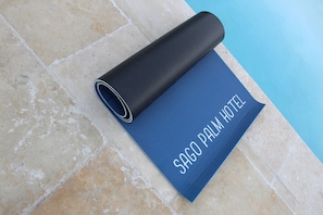 A blue mat with "SAGO PALM HOTEL" text on a tiled floor near a pool.