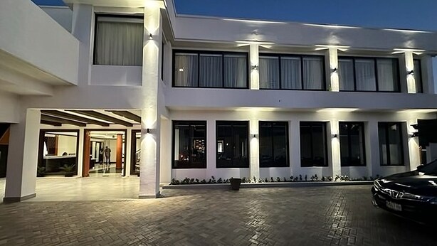 A modern two-story building with a paved courtyard and a car parked in front. - Sago Palm Hotel (Ocho Rios)