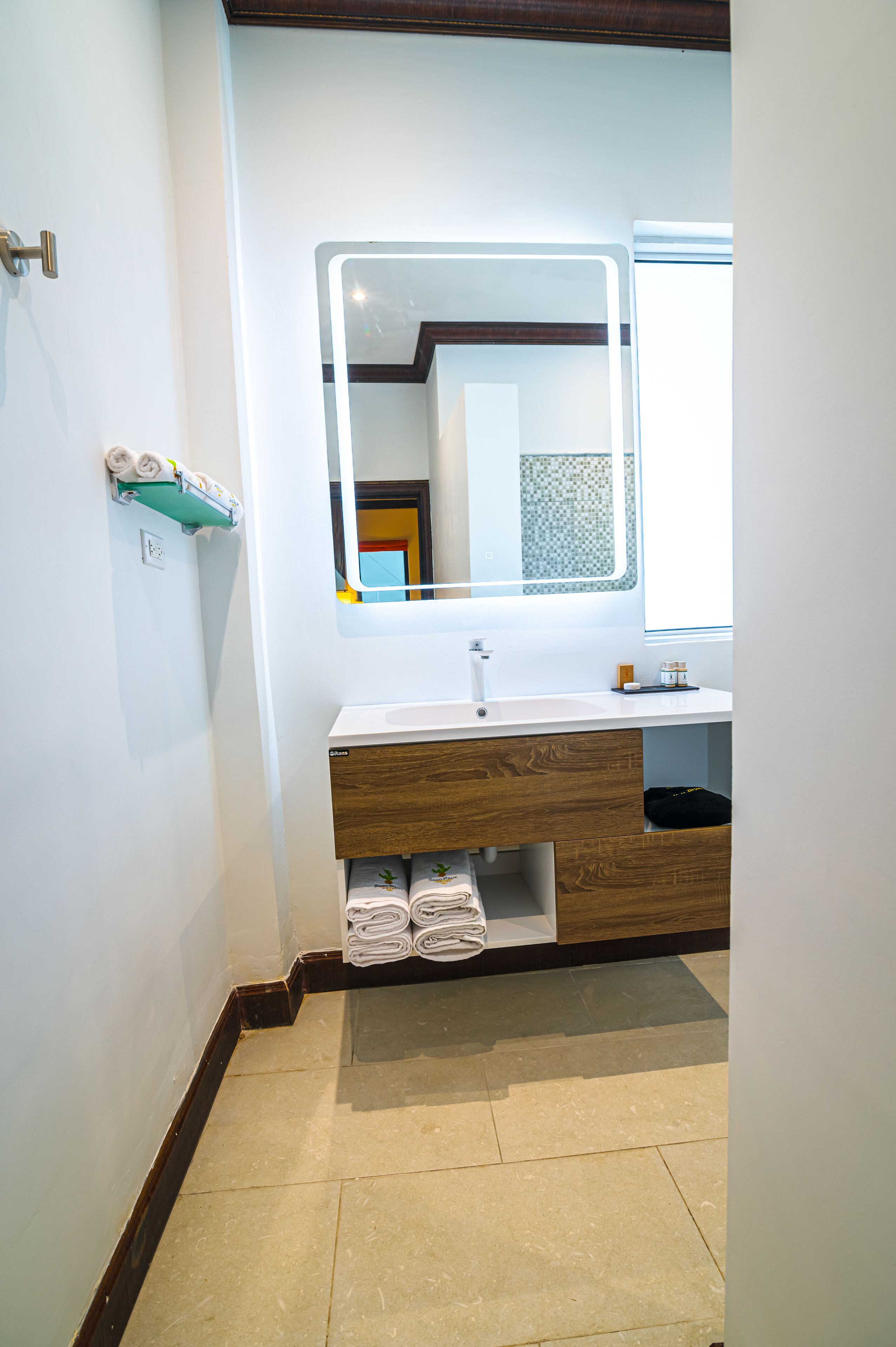 A bathroom with a white sink, wooden vanity, and a mirror.