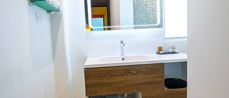 Une salle de bain avec un lavabo blanc, un meuble-lavabo en bois et un miroir.