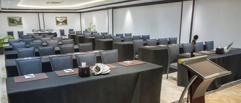 A conference room with rows of tables and chairs, equipped with microphones and nameplates.