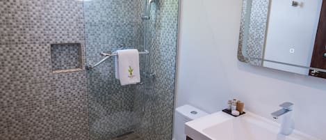 A modern bathroom with a glass-enclosed shower, a round skylight, a white toilet, and a vanity with a mirror.