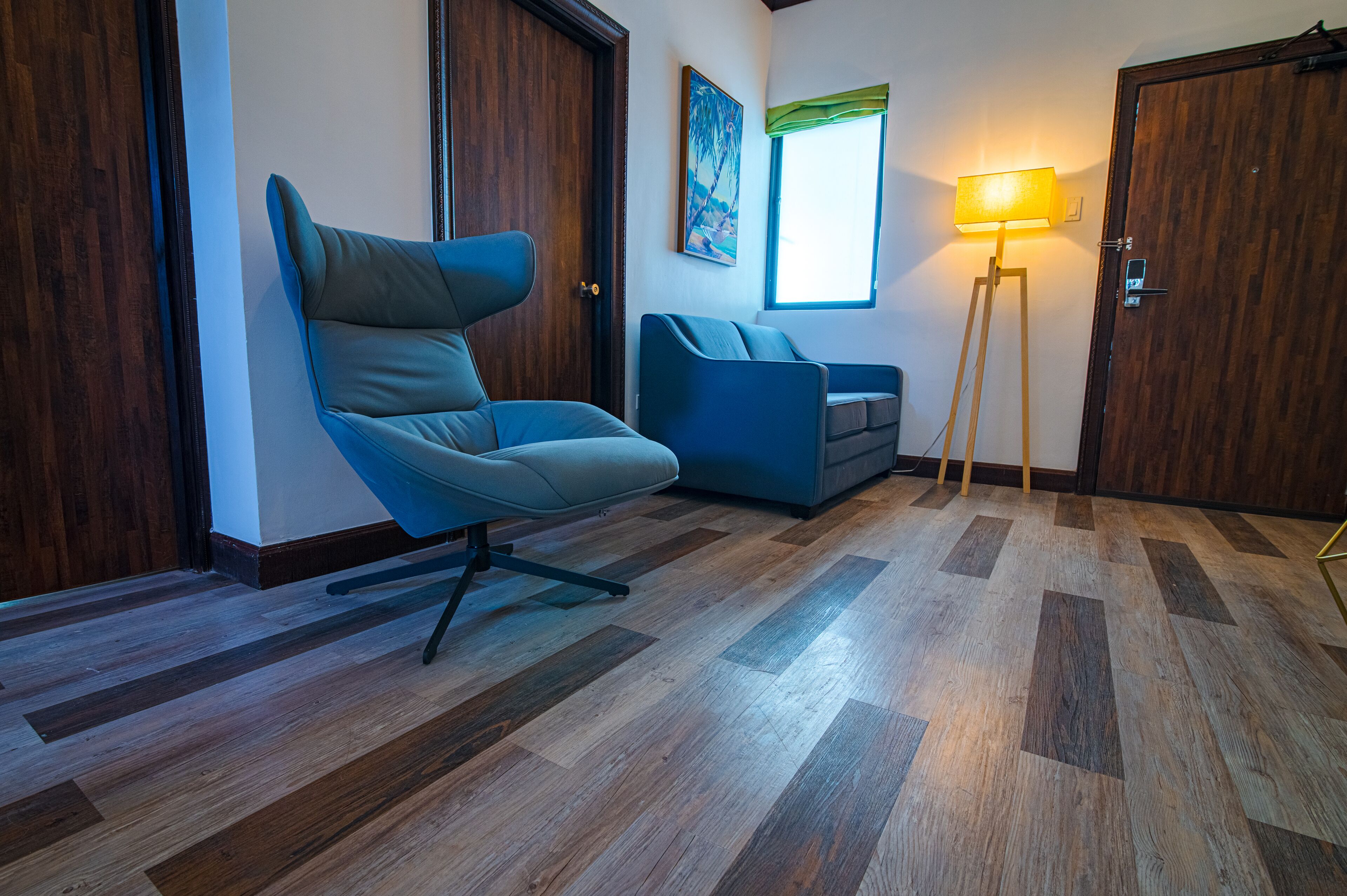 A modern living room with a blue sofa, a blue armchair, and a floor lamp.