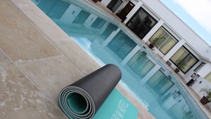 A pool area with a yoga mat and a building in the background. - Sago Palm Hotel (Ocho Rios)