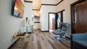 A modern living room with a TV, a bar area, and a seating area. - Sago Palm Hotel (Ocho Rios)