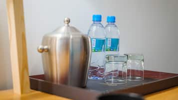 A stainless steel coffee maker, two water bottles, and two empty glasses on a tray.