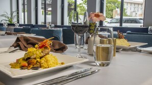 A restaurant setting with a table set for a meal, including plates of food, wine glasses, and cutlery. - Sago Palm Hotel (Ocho Rios)