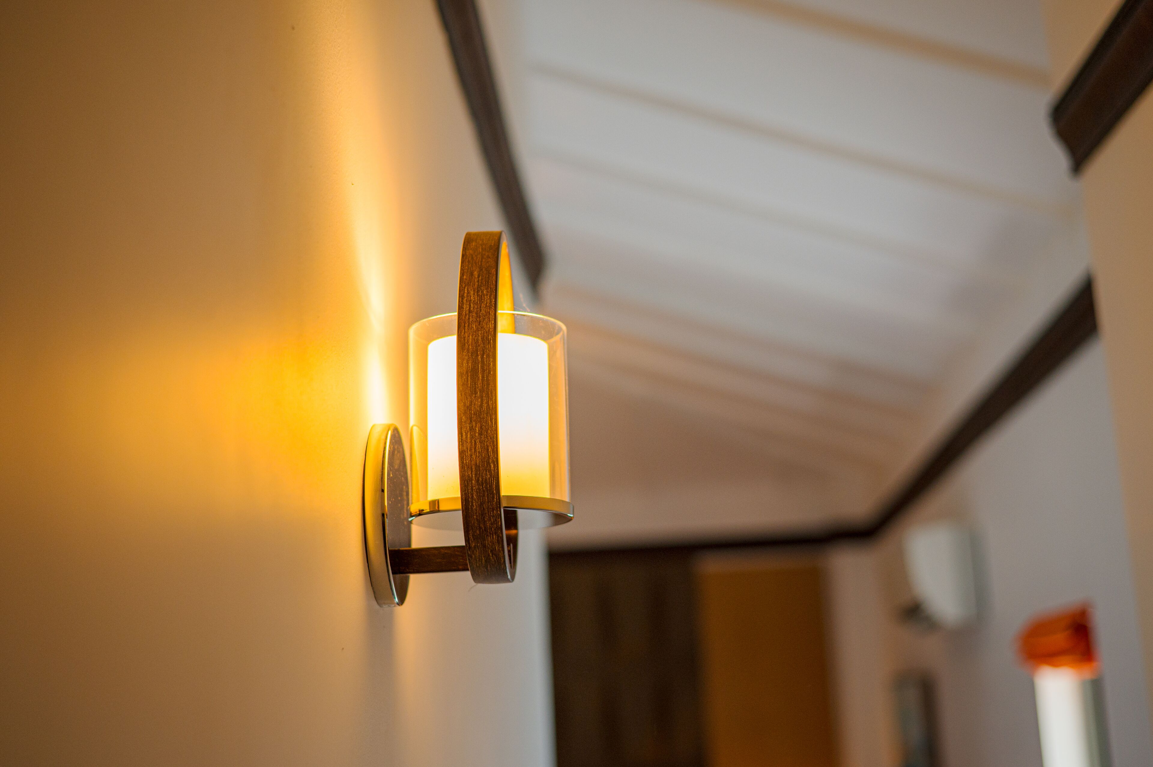 A wall-mounted light fixture with a wooden frame and a cylindrical glass shade.