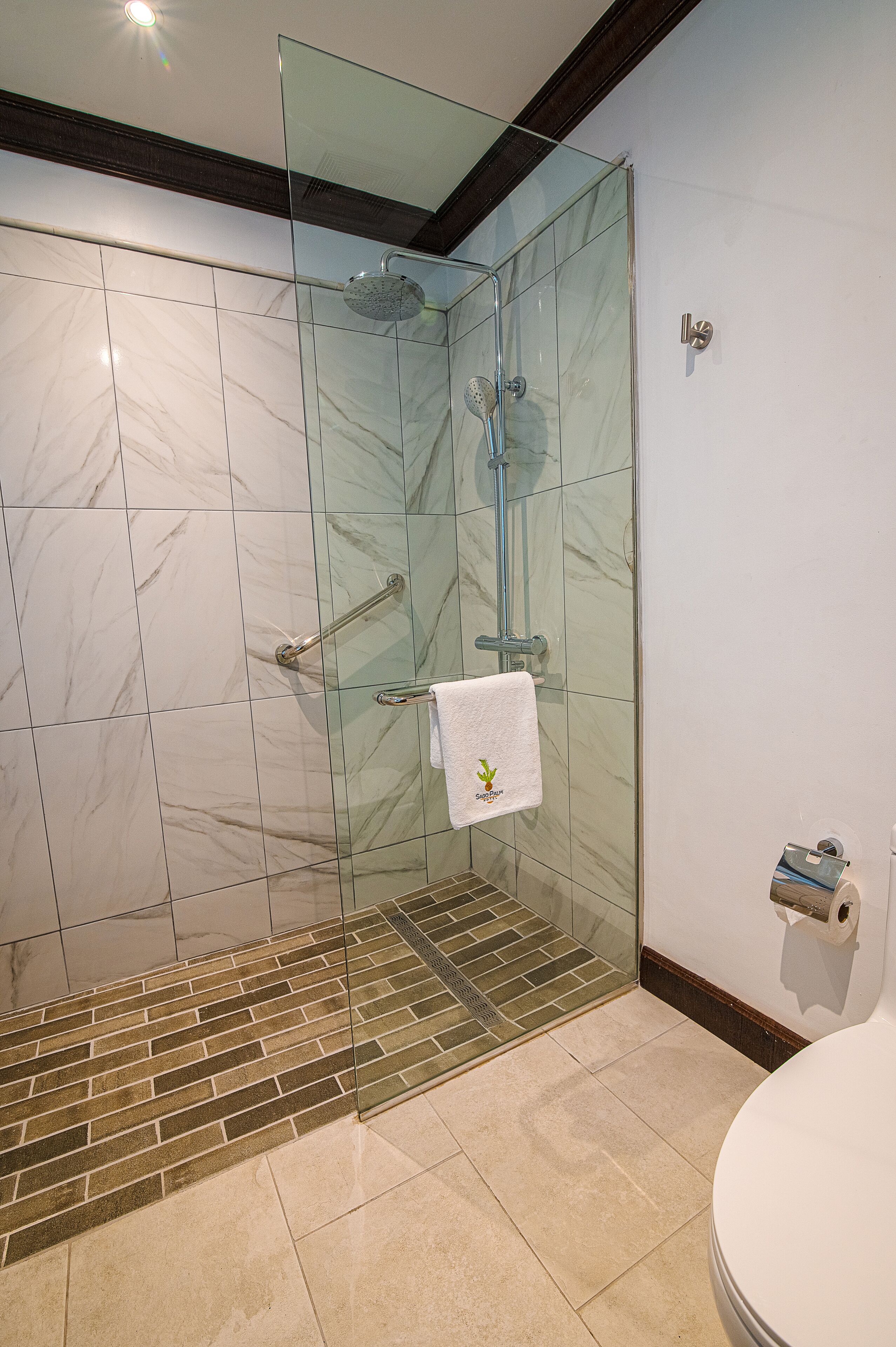 Un bagno moderno con doccia vetrata, piastrelle in marmo e water bianco.