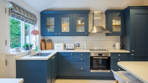 Une cuisine moderne avec des meubles de couleur bleu foncé, un four Bosch et une fenêtre donnant sur un paysage verdoyant.