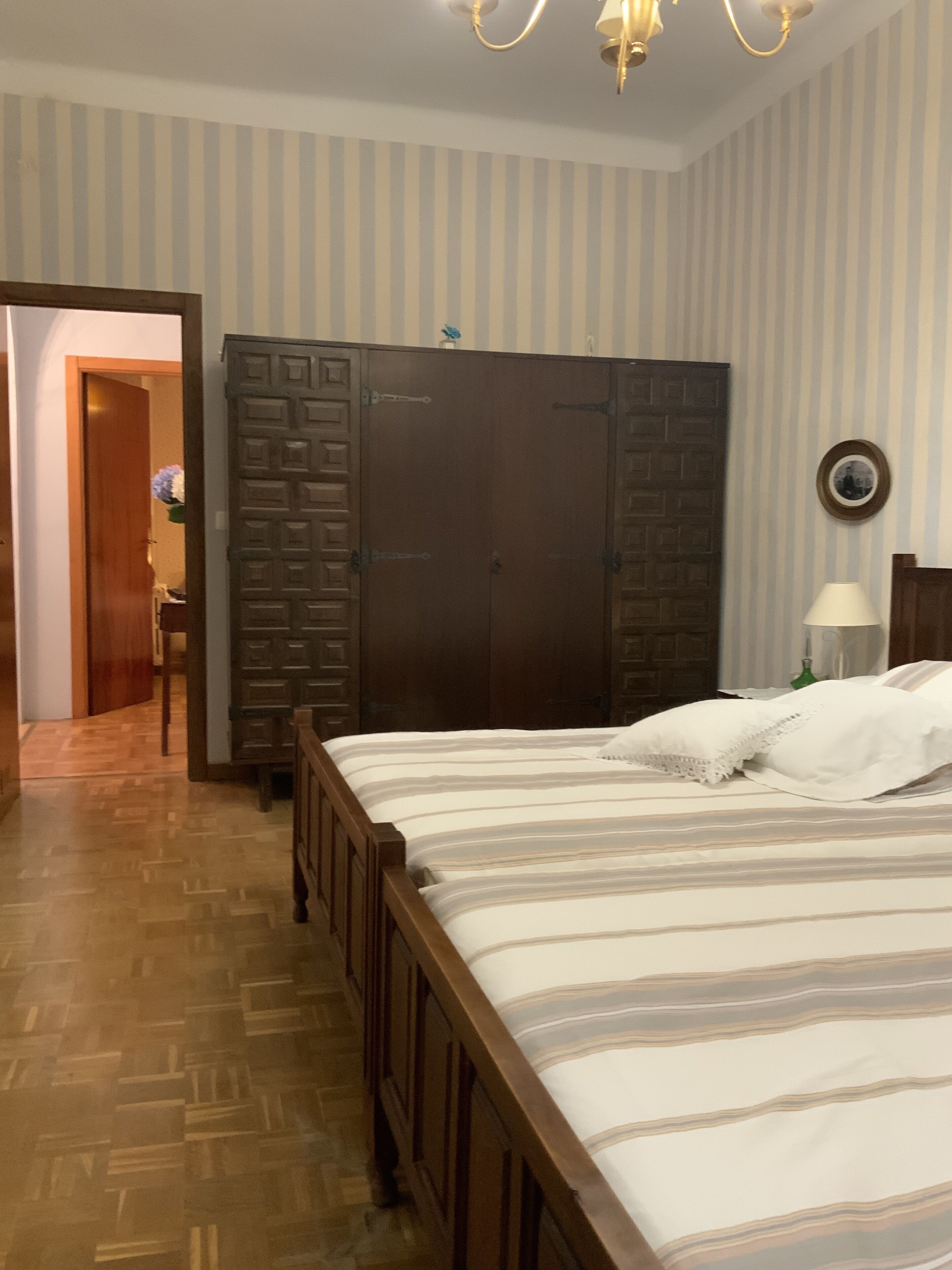 Un dormitorio con una cama de madera, un armario y un espejo en la pared.