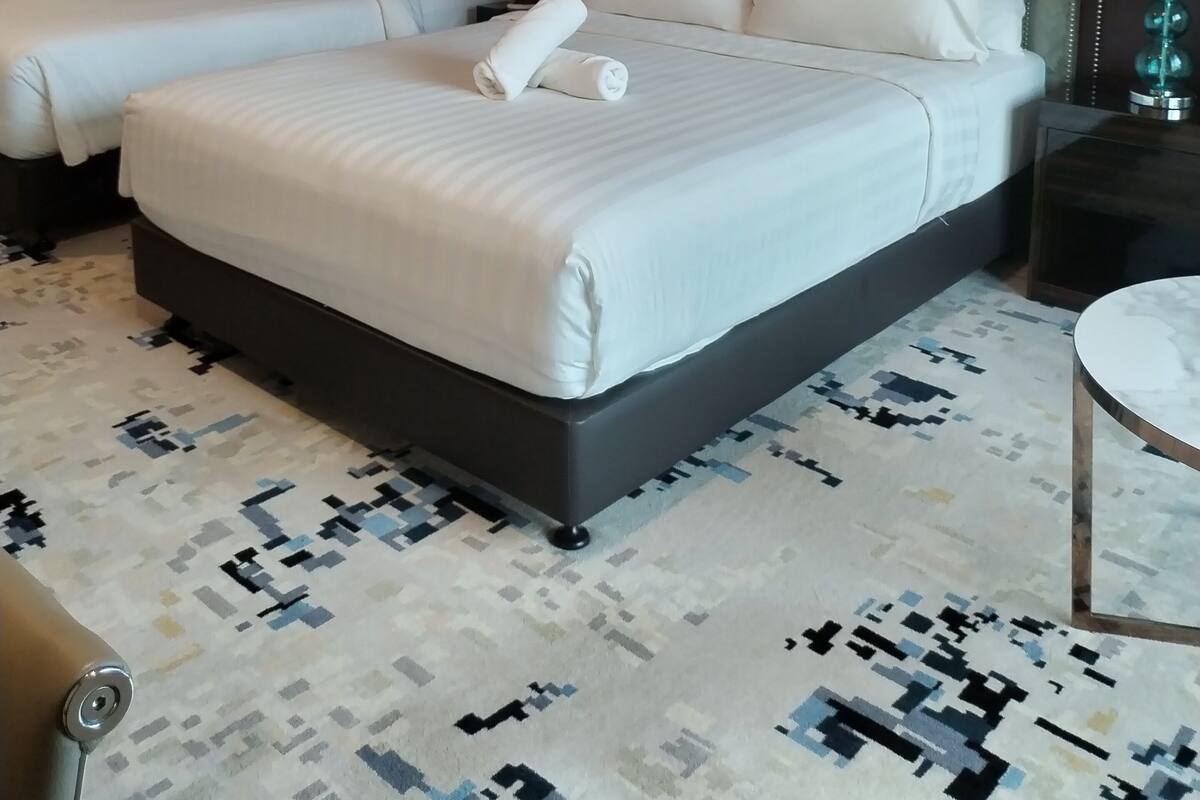 A hotel room with two beds, a patterned carpet, and a small round table.