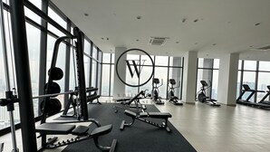 A modern gym with various exercise equipment, large windows, and a city view. - Victory suites  (Kuala Lumpur)