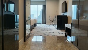A modern hotel room with a large bed, a desk, a chair, and a TV. - Victory suites  (Kuala Lumpur)