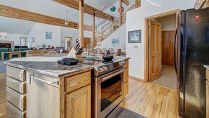 Een ruime keuken met houten balken, een groot kookeiland en een moderne kookplaat.