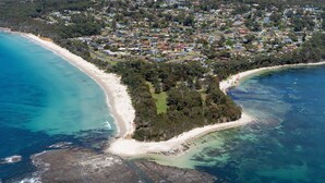 Ein Luftbild einer Küstenstadt mit Strand, Wohngebiet und klarem, blauem Wasser.