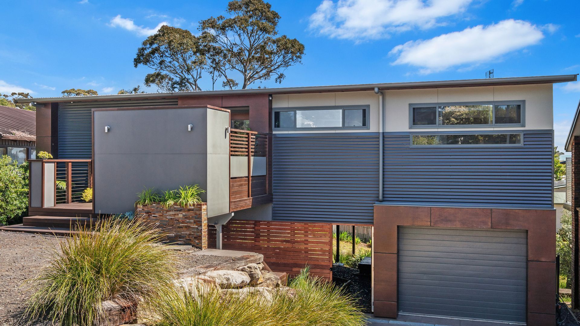 A modern two-story house with a flat roof, large windows, and a garage.