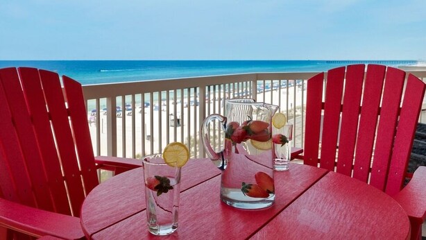 Una mesa con dos jarras y un vaso en un balcón con vista al mar.