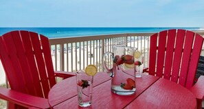 Ein Tisch mit zwei Karaffen und einem Glas auf einem Balkon mit Blick auf den Strand.