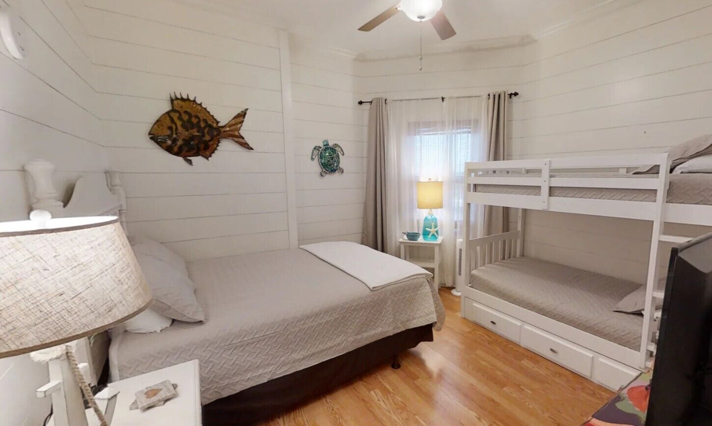 Une chambre avec un lit superposé, un lit simple, une lampe et des décorations murales, notamment un poisson et une tortue.