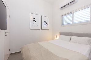 A bedroom with a bed, a TV, and two framed pictures on the wall.