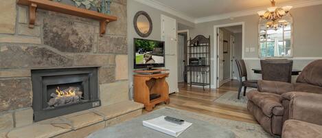 A living room with a stone fireplace, a television, and a cozy seating area.
