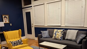 Ein Wohnzimmer mit einem gelben Sessel, einem grauen Sofa und einem gemusterten Teppich.