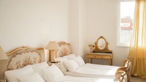 Habitación de hotel con cama doble, mesita de noche, cómoda con espejo y ventana con cortinas.