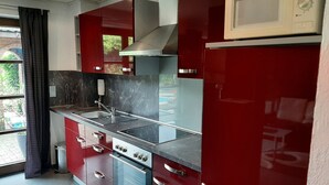 Une cuisine moderne avec des meubles de rangement rouges, un évier en acier inoxydable et un four encastré.