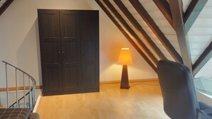 Une pièce avec une armoire en bois, une lampe, une chaise et un escalier.