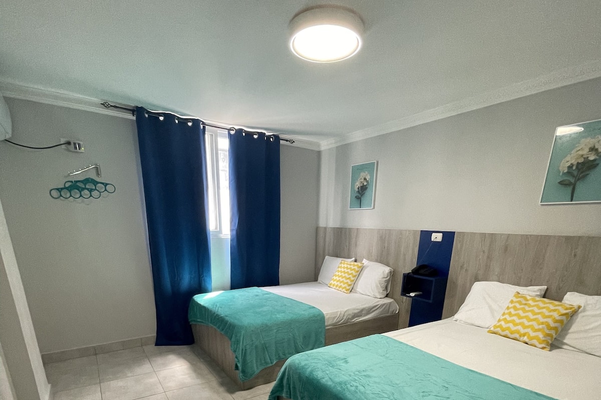 A hotel room with two beds, a bathroom, and a shower area.