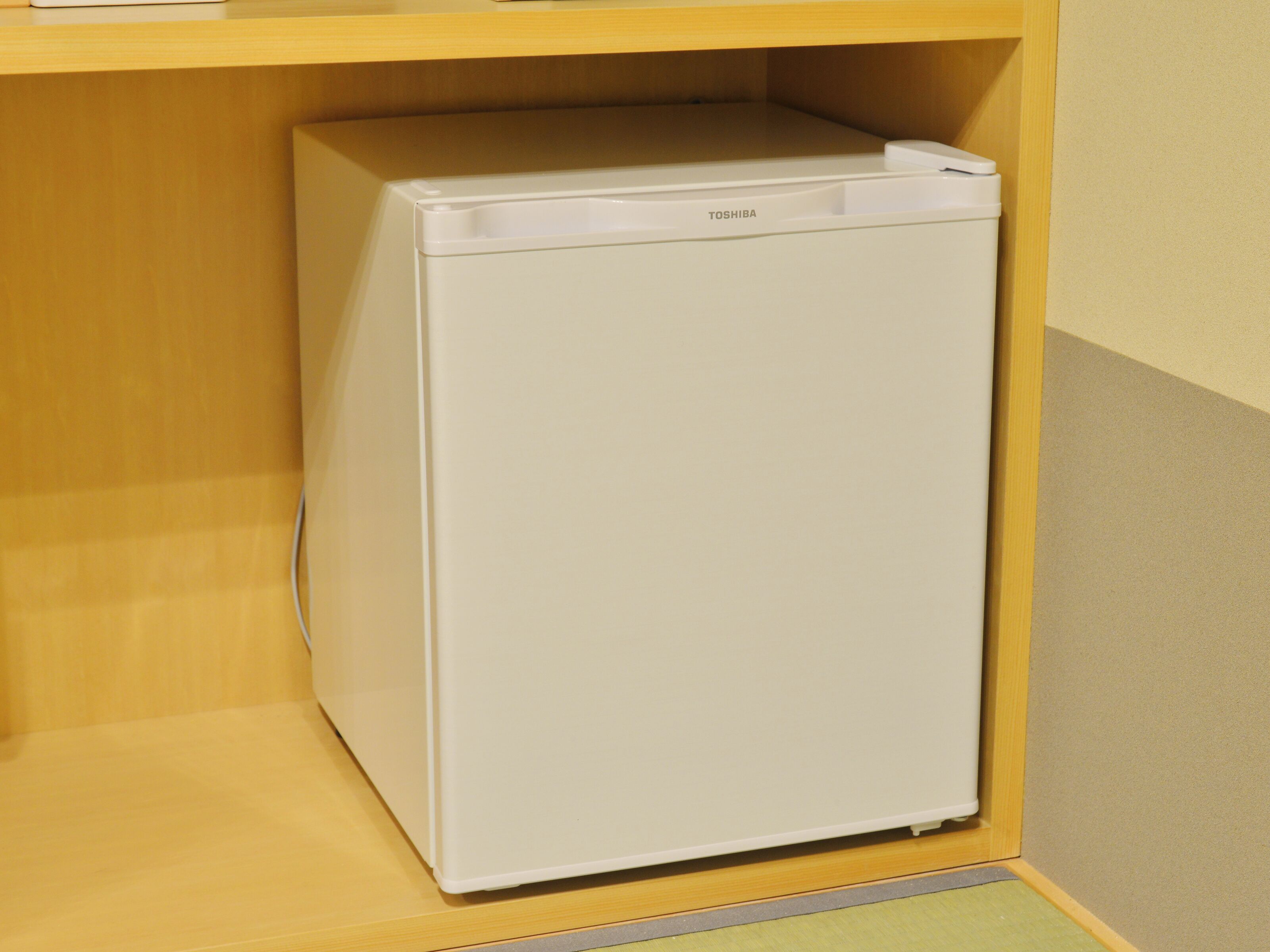 A white refrigerator in a kitchen with wooden cabinets and a beige countertop.