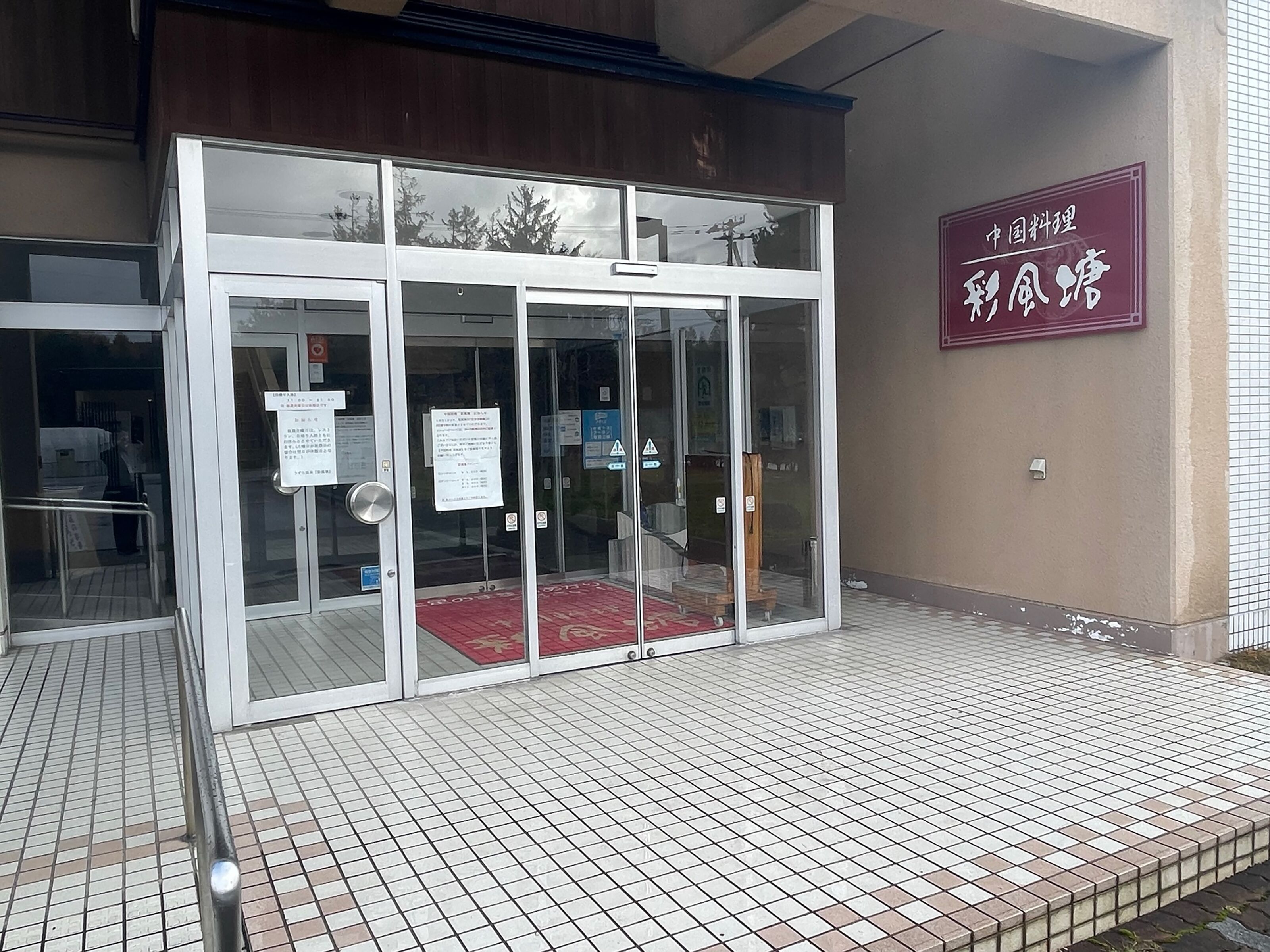 A building entrance with a glass door and a red mat at the entrance.