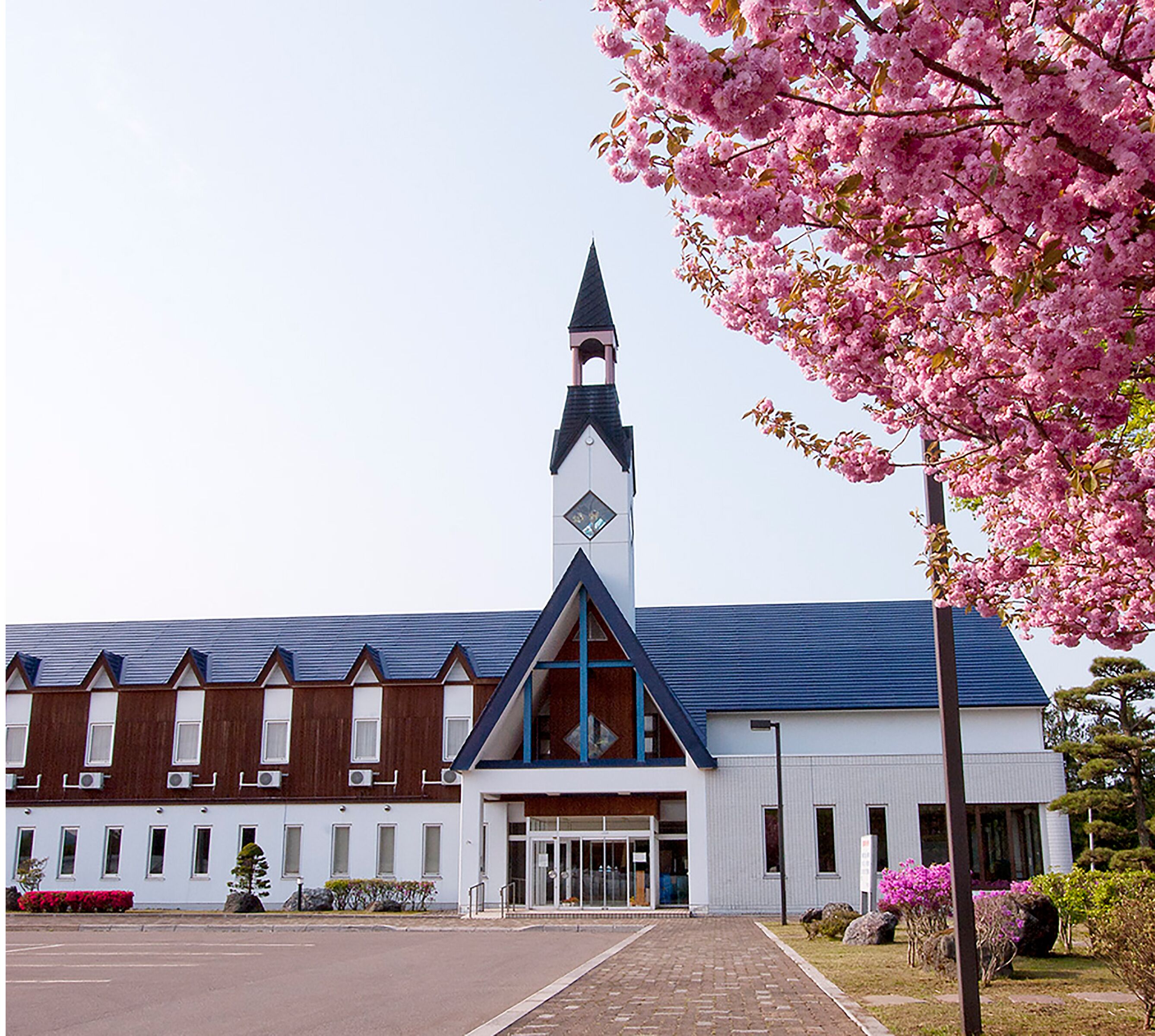Una iglesia con un campanario alto y un edificio moderno con techo azul.