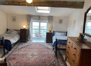 Quarto com duas camas, um tapete grande, uma cômoda e uma janela com cortinas.