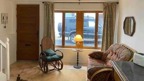 Une pièce avec une fenêtre à cadre en bois, une chaise, un canapé et une lampe.