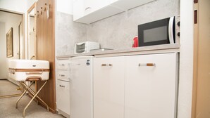 Una cocina compacta con microondas, tostadora y refrigerador.