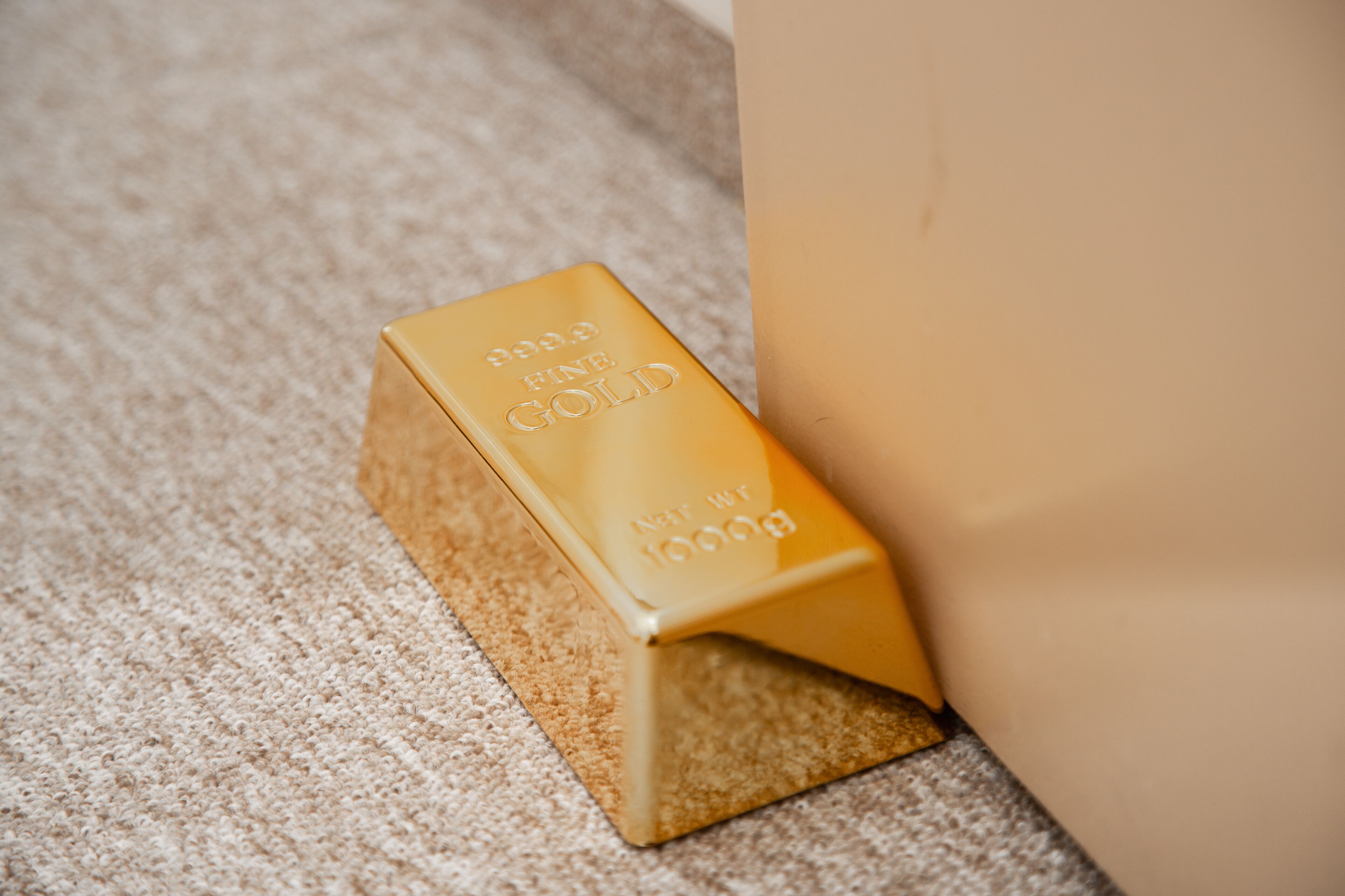 A gold bar with "999.9 Fine Gold" and "Net Weight 1000g" on a textured surface.