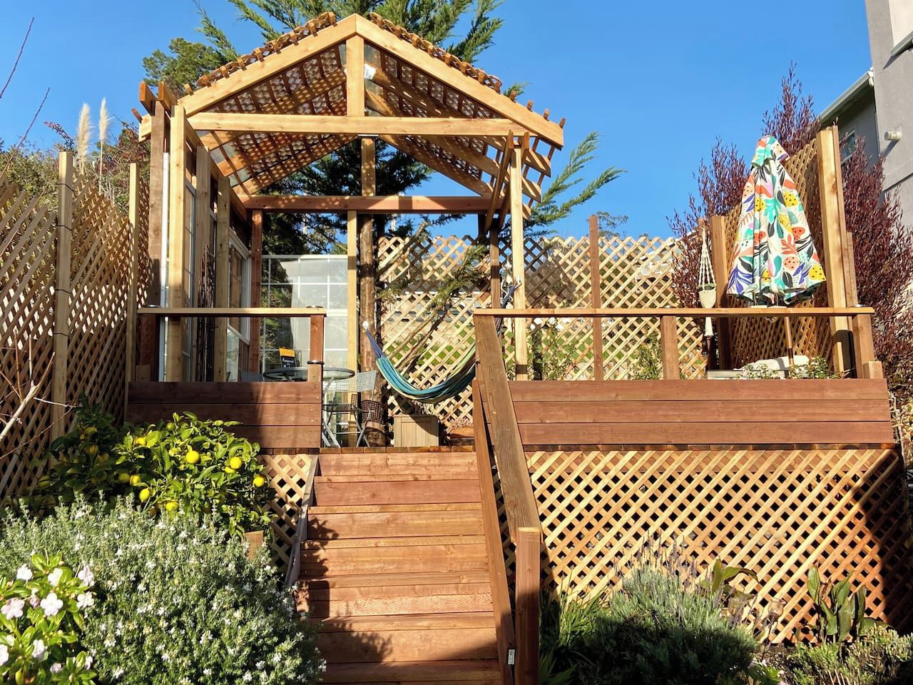 Une terrasse en bois agrémentée d’une pergola, d’un hamac et d’une clôture en bois.