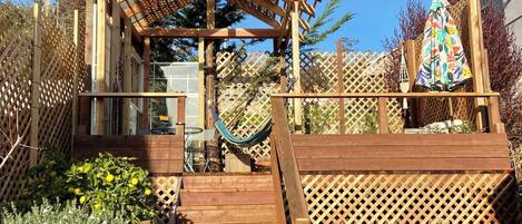 A wooden deck with a pergola, a hammock, and a wooden fence.