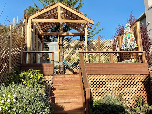 A wooden deck with a pergola, a hammock, and a wooden fence. - Oceanview Penthouse, Stylish, Walking to Beach (Half Moon Bay)