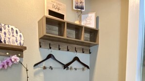 Een werkplek aan huis met een bureau, een plank met hangende spullen en opbergmanden.