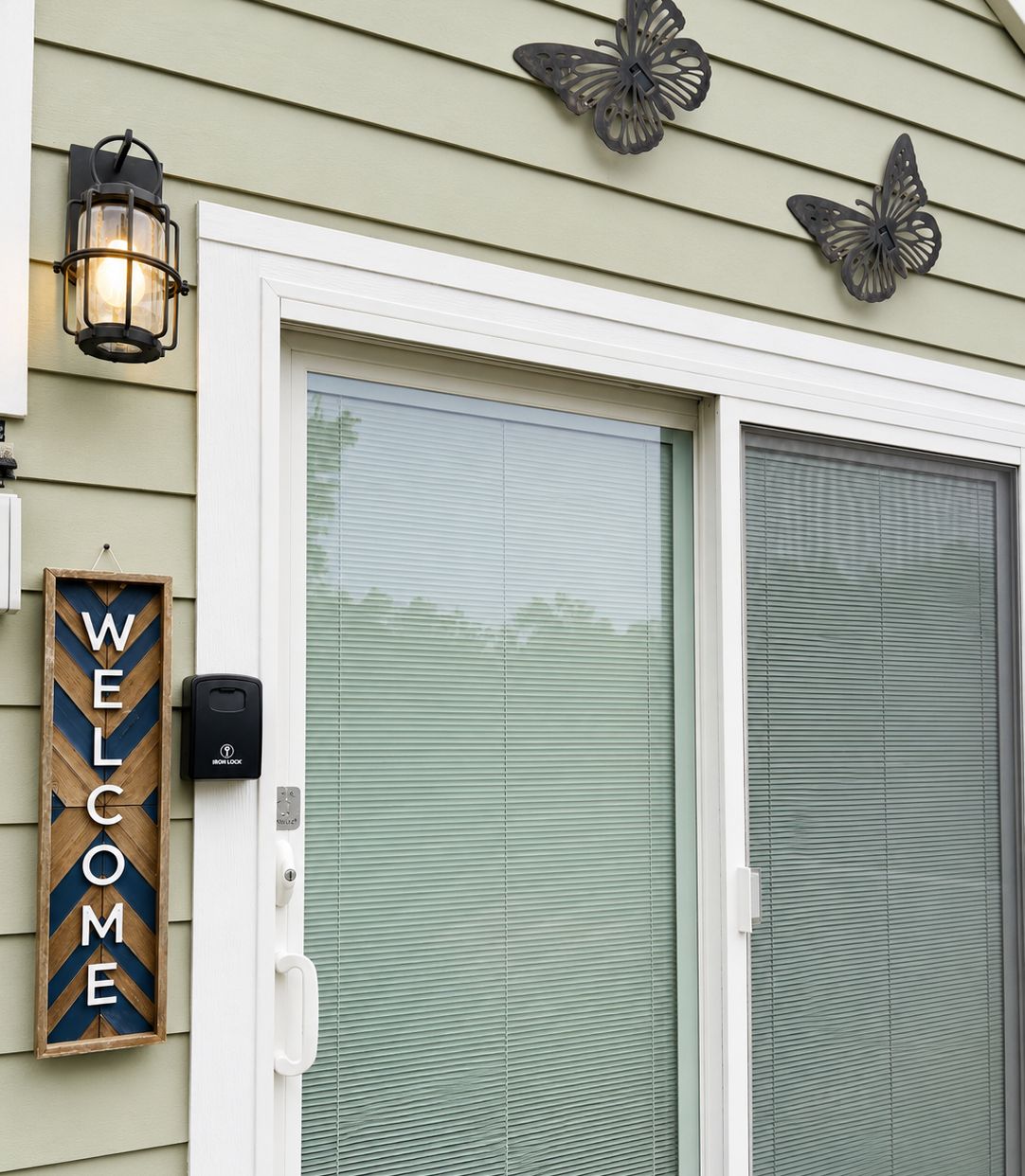 Une entrée de maison agrémentée d’une pancarte « BIENVENUE », d’une sonnette et de découpes décoratives en forme de papillons.